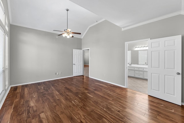 unfurnished bedroom featuring wood finished floors, baseboards, lofted ceiling, ensuite bathroom, and crown molding