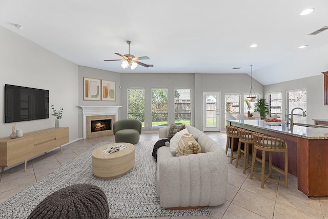 living area with visible vents, a lit fireplace, light tile patterned floors, recessed lighting, and a ceiling fan