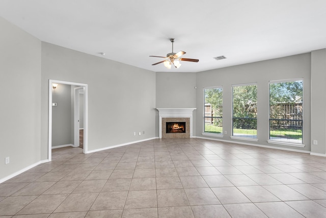 unfurnished living room featuring a ceiling fan, visible vents, baseboards, light tile patterned flooring, and a tiled fireplace