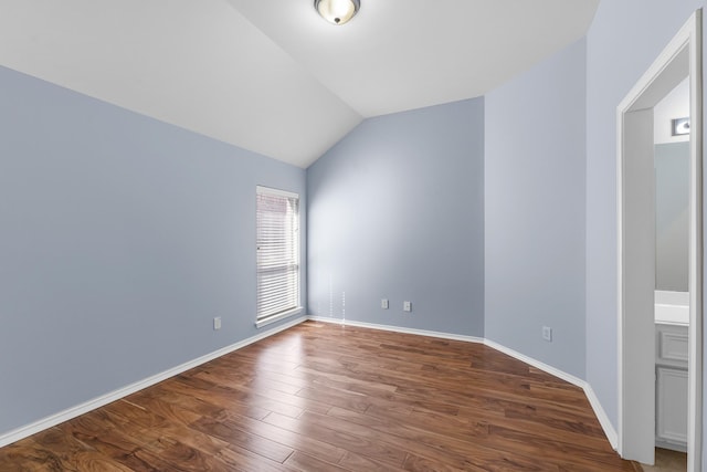 empty room featuring dark wood finished floors, baseboards, and lofted ceiling