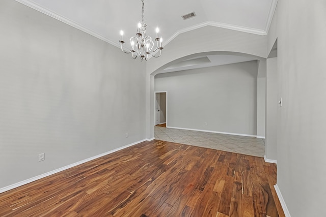 unfurnished room featuring wood finished floors, arched walkways, crown molding, a chandelier, and vaulted ceiling