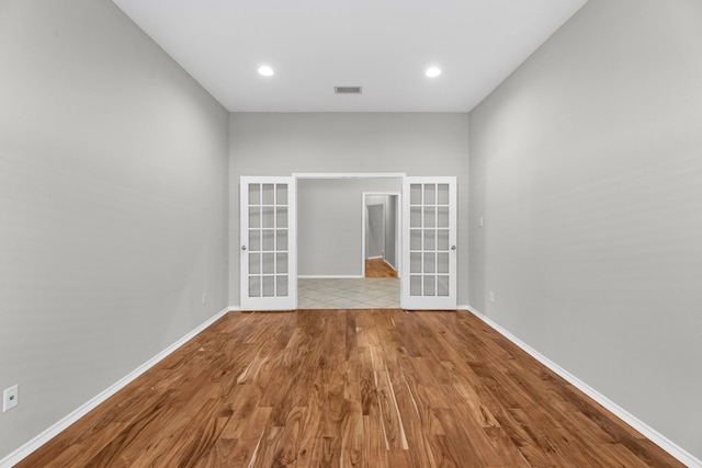 spare room with french doors, baseboards, visible vents, and wood finished floors