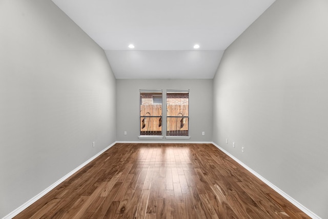 unfurnished room with baseboards, dark wood-type flooring, and vaulted ceiling