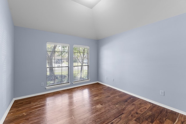 unfurnished room with dark wood-type flooring, baseboards, and vaulted ceiling