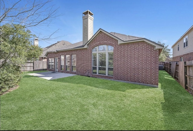 back of property with a patio, a yard, a fenced backyard, and brick siding