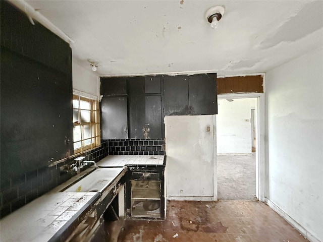 kitchen featuring tile countertops, backsplash, and a sink