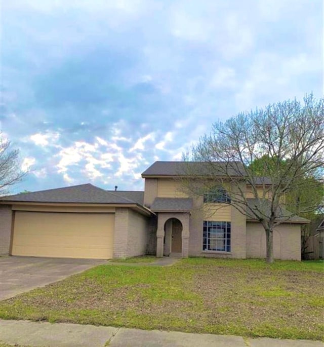 view of front facade with driveway, a garage, a front lawn, and brick siding