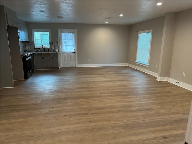 interior space featuring light wood-type flooring, baseboards, a sink, and recessed lighting