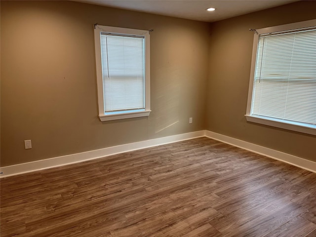 spare room with dark wood-type flooring, recessed lighting, and baseboards