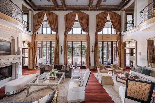 living room featuring coffered ceiling, a premium fireplace, wood finished floors, a high ceiling, and beam ceiling