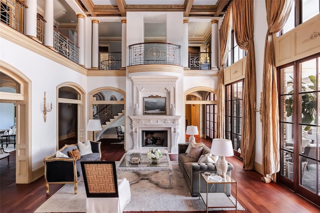 living area featuring baseboards, a fireplace, a high ceiling, and wood finished floors