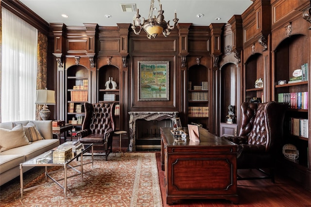 living area with built in features, a notable chandelier, visible vents, a premium fireplace, and wood finished floors