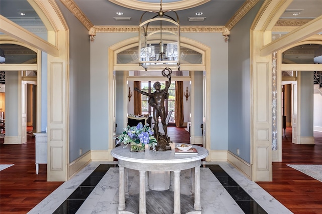 entryway with crown molding, baseboards, a chandelier, and wood finished floors