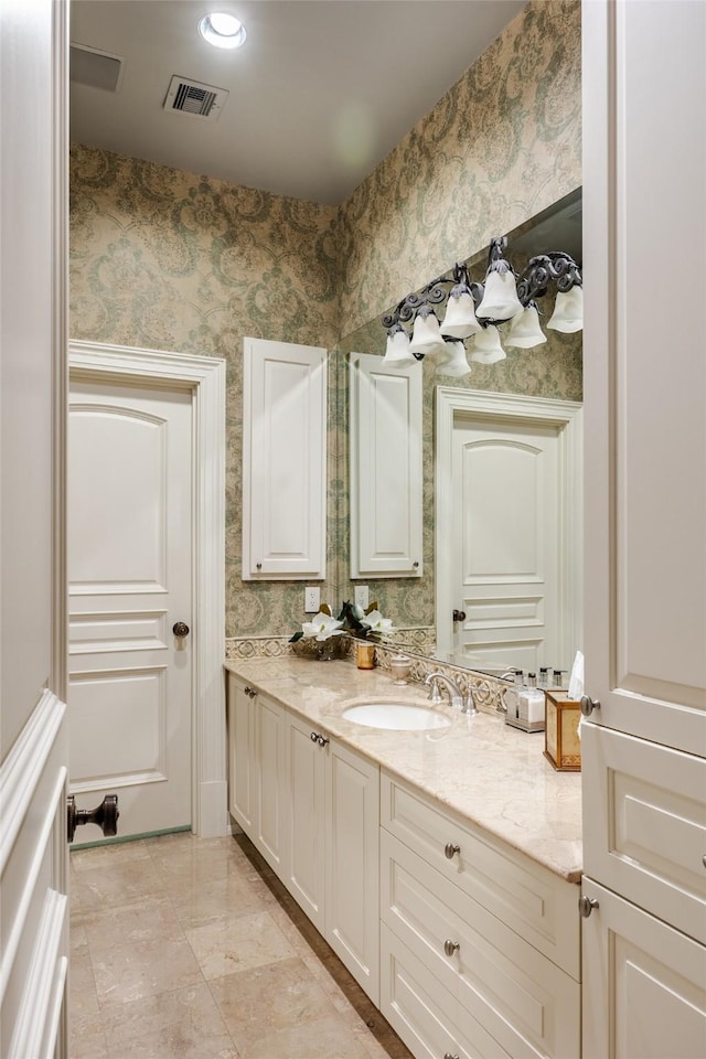 bathroom with vanity, visible vents, and wallpapered walls