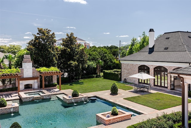 view of pool featuring a yard, exterior fireplace, a patio area, and a pool with connected hot tub