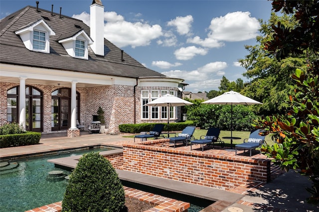 back of house with brick siding, a patio area, and an outdoor pool