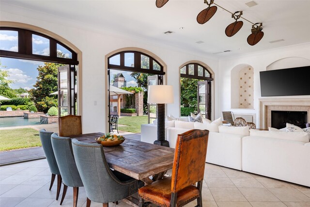 dining room with ornamental molding, light tile patterned flooring, ceiling fan, and a fireplace