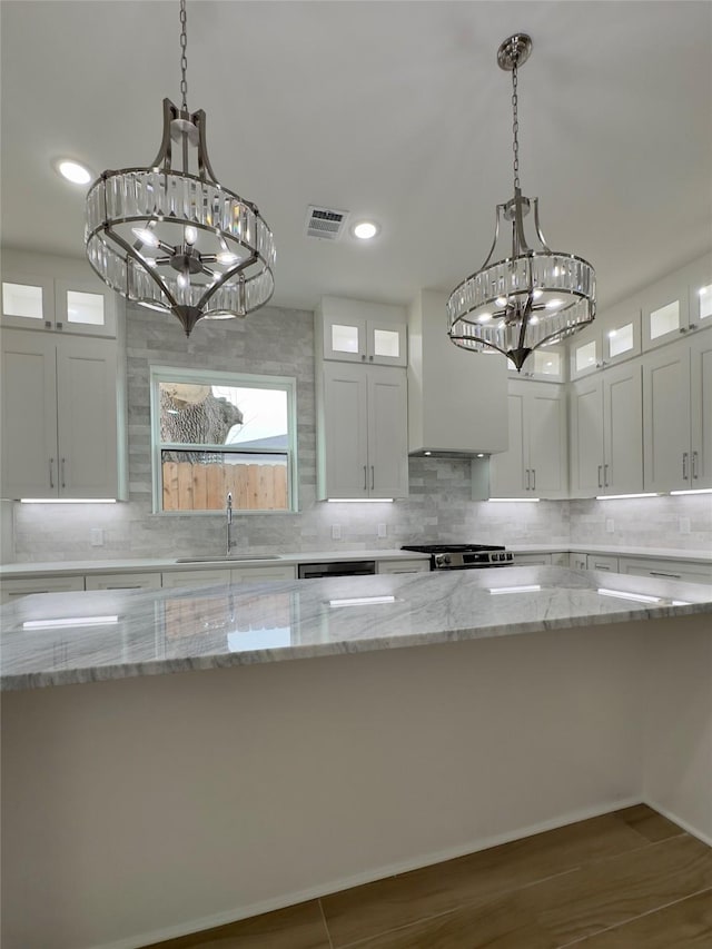 kitchen with a chandelier, wall chimney exhaust hood, a sink, and visible vents