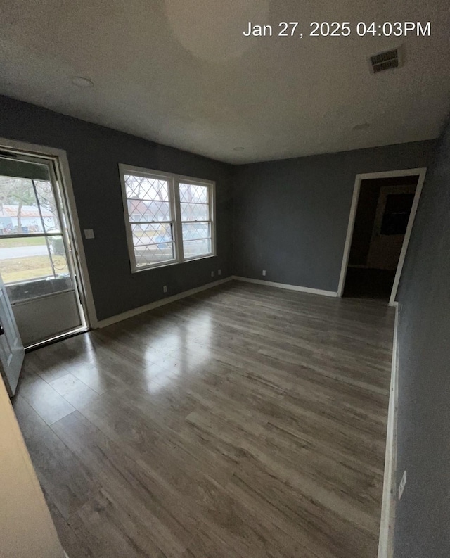 interior space featuring a textured ceiling, wood finished floors, visible vents, and baseboards