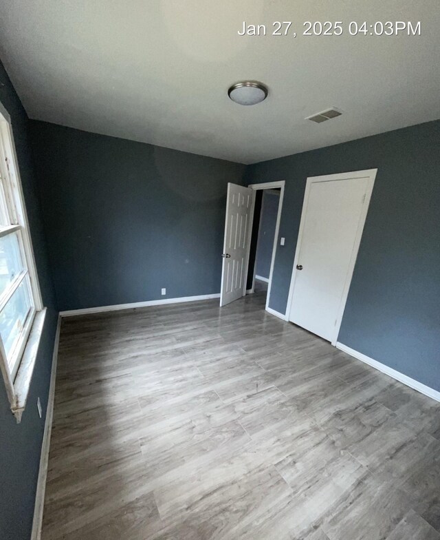 unfurnished room with wood finished floors, visible vents, and baseboards