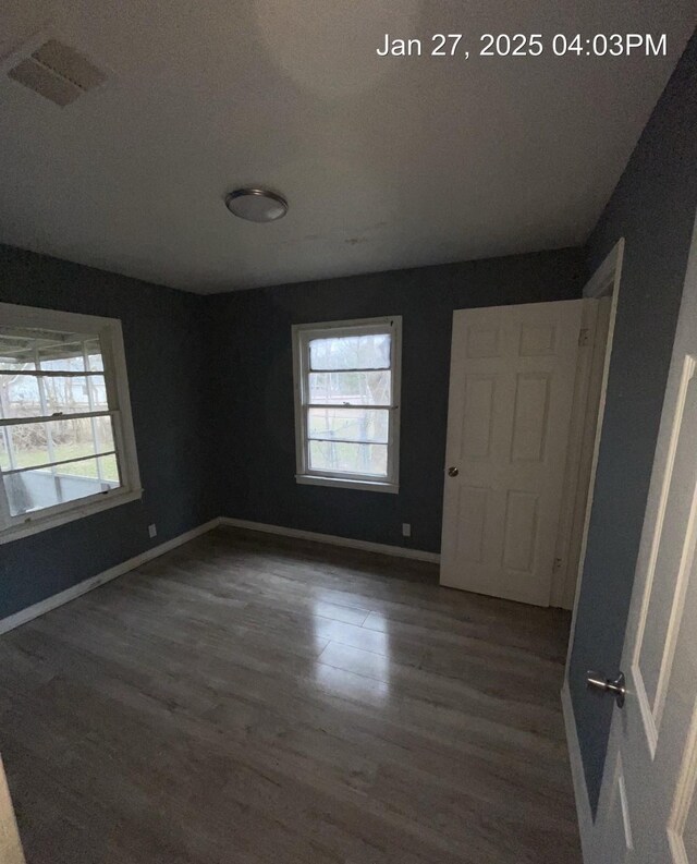 unfurnished bedroom featuring visible vents, baseboards, and wood finished floors