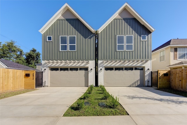 view of front of house with an attached garage, driveway, fence, and board and batten siding