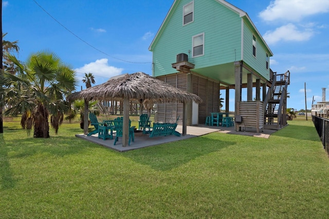 back of house with stairway, fence, a gazebo, a patio area, and a lawn