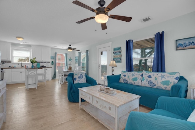 living area with light wood-style floors, a ceiling fan, and visible vents