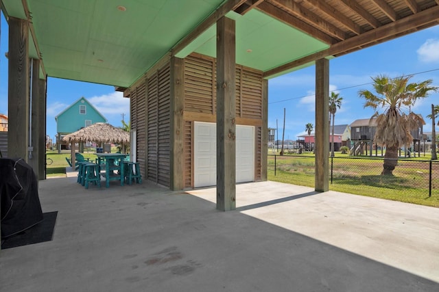 view of patio featuring a garage, outdoor dining area, and fence