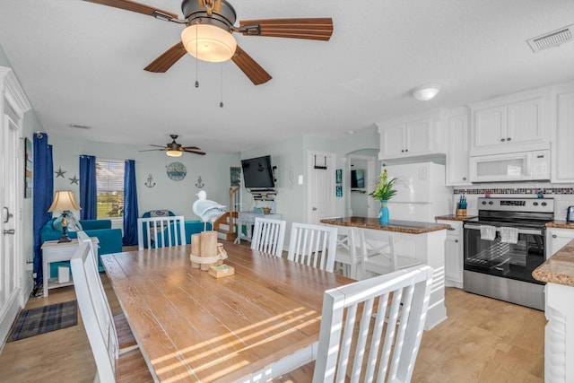 dining space with visible vents, light wood-type flooring, and ceiling fan