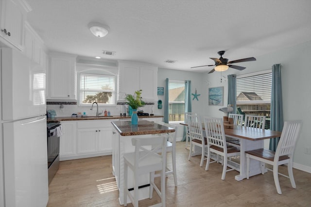 kitchen featuring electric range, plenty of natural light, visible vents, and freestanding refrigerator