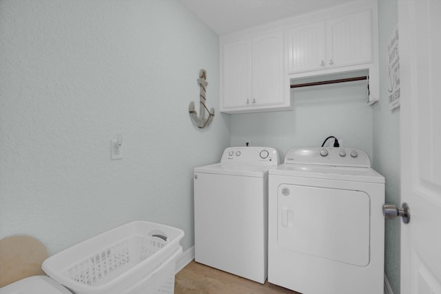 laundry room with light wood-type flooring, cabinet space, and separate washer and dryer