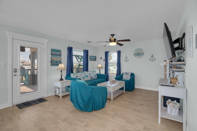 living area featuring visible vents, baseboards, a ceiling fan, and light wood finished floors