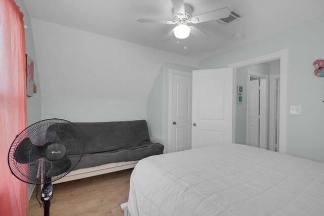 bedroom with lofted ceiling, wood finished floors, visible vents, and ceiling fan