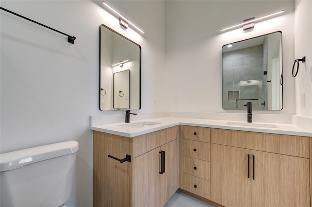 bathroom with toilet, double vanity, an enclosed shower, and a sink