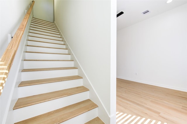 stairway with baseboards, visible vents, wood finished floors, and recessed lighting