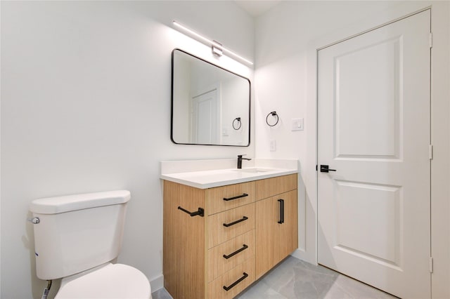 bathroom with toilet, marble finish floor, and vanity