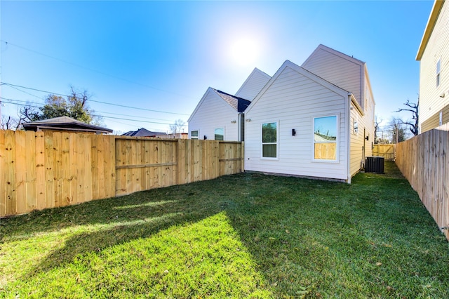 back of house with a fenced backyard, central AC, and a yard