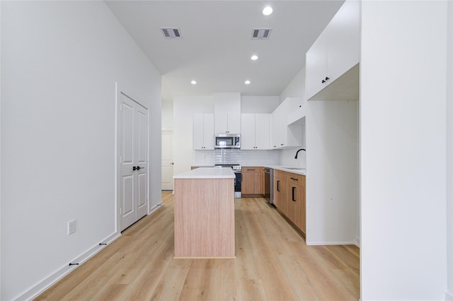 kitchen featuring stainless steel appliances, backsplash, a kitchen island, and visible vents