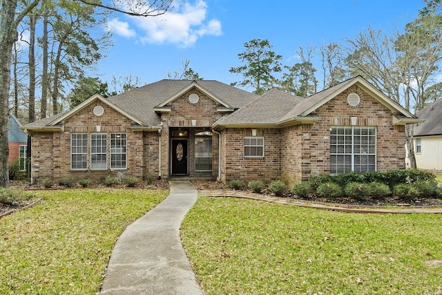 view of front of home featuring brick siding, a shingled roof, and a front lawn