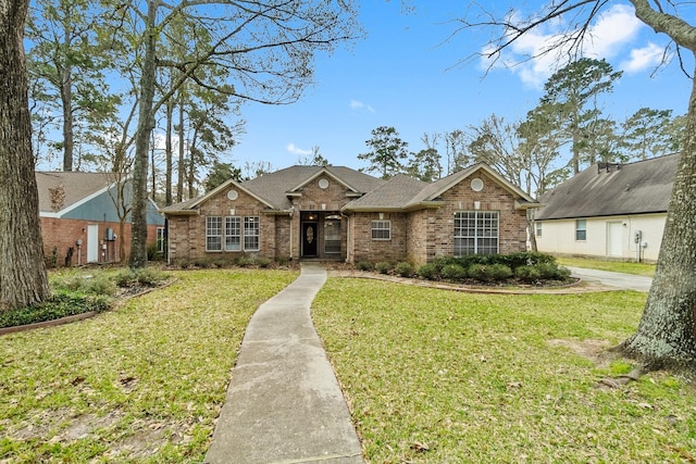 view of front facade with brick siding, roof with shingles, and a front yard