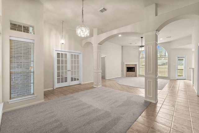 unfurnished living room with visible vents, a fireplace, ceiling fan, and a towering ceiling