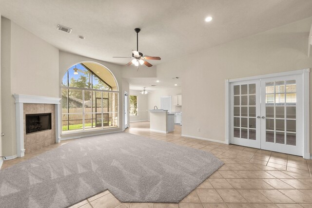 unfurnished living room with visible vents, a ceiling fan, french doors, a fireplace, and light tile patterned floors