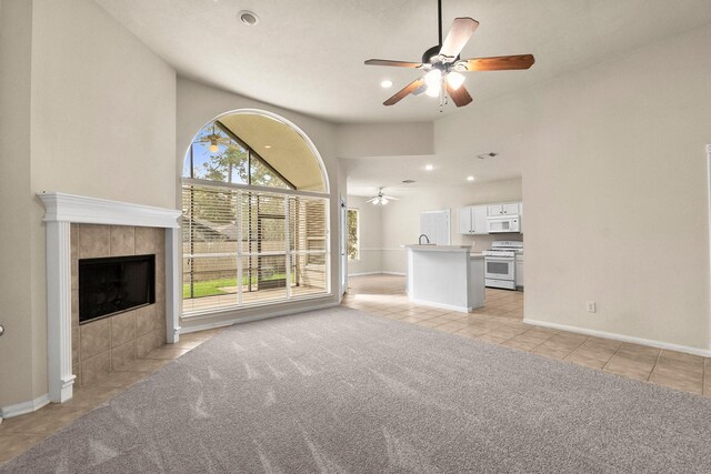 unfurnished living room featuring light carpet, a tiled fireplace, recessed lighting, light tile patterned flooring, and ceiling fan