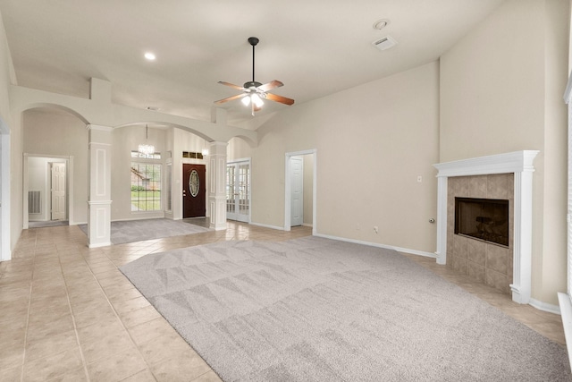 unfurnished living room with visible vents, ceiling fan, decorative columns, a fireplace, and arched walkways