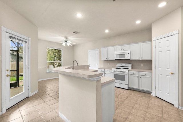 kitchen with light countertops, recessed lighting, white cabinets, white appliances, and a kitchen island with sink