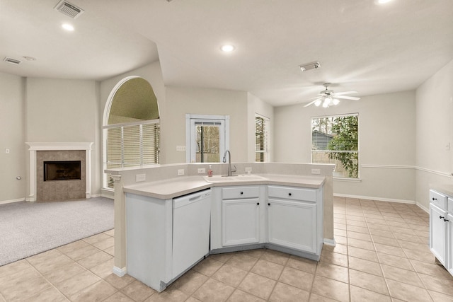 kitchen with visible vents, white dishwasher, a tile fireplace, a sink, and open floor plan