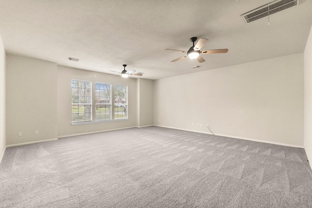 carpeted empty room with visible vents, baseboards, and a ceiling fan