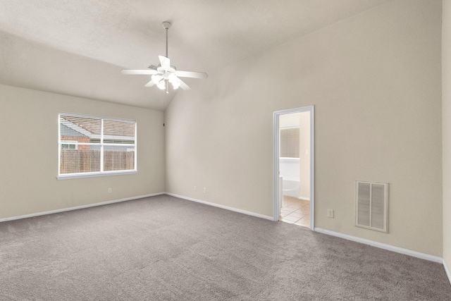 unfurnished room with visible vents, lofted ceiling, a ceiling fan, carpet floors, and baseboards