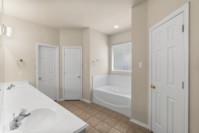 bathroom with a sink, baseboards, a bath, and double vanity